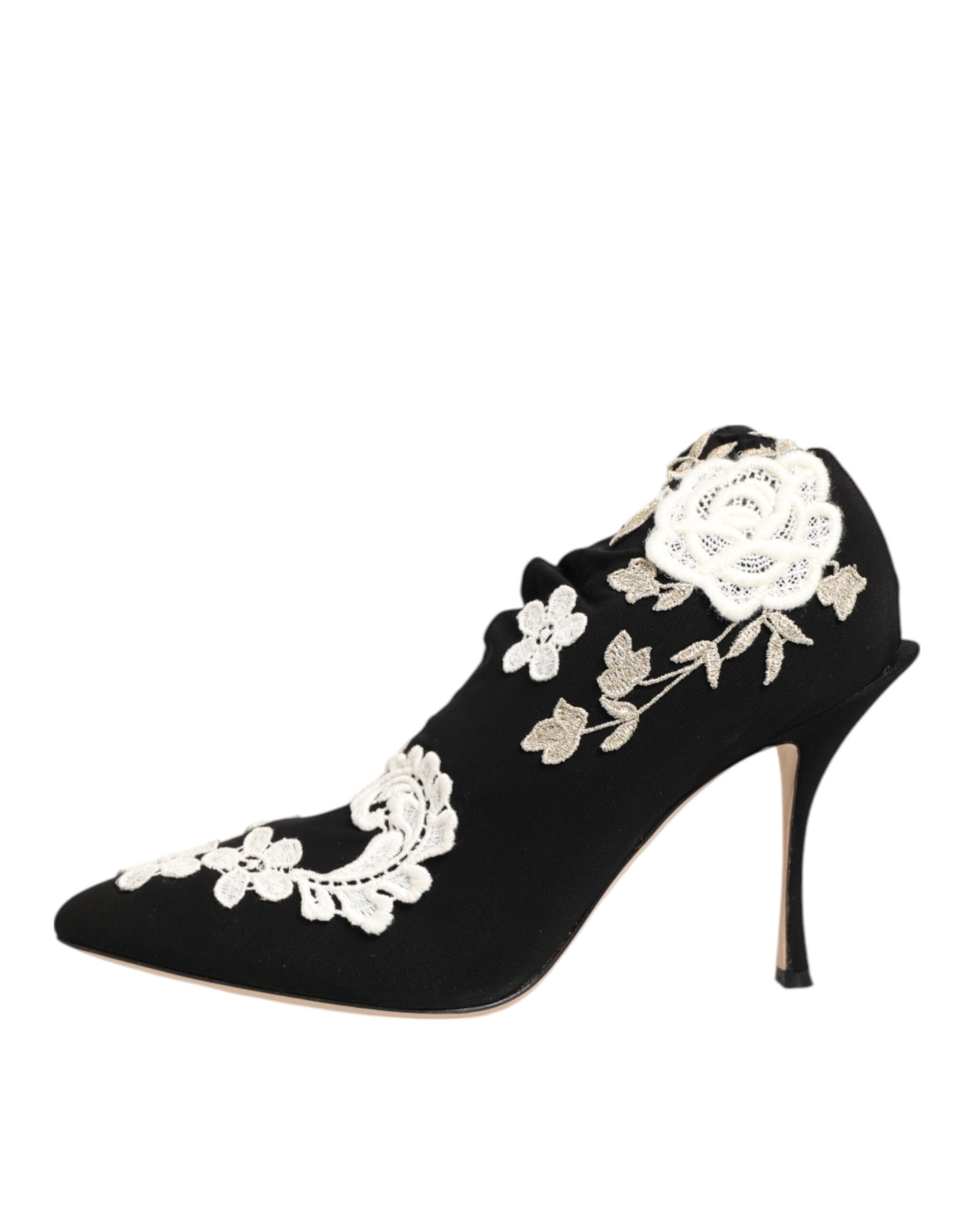 Black pointed-toe stiletto pump featuring intricate white lace floral embroidery on a soft fabric upper.