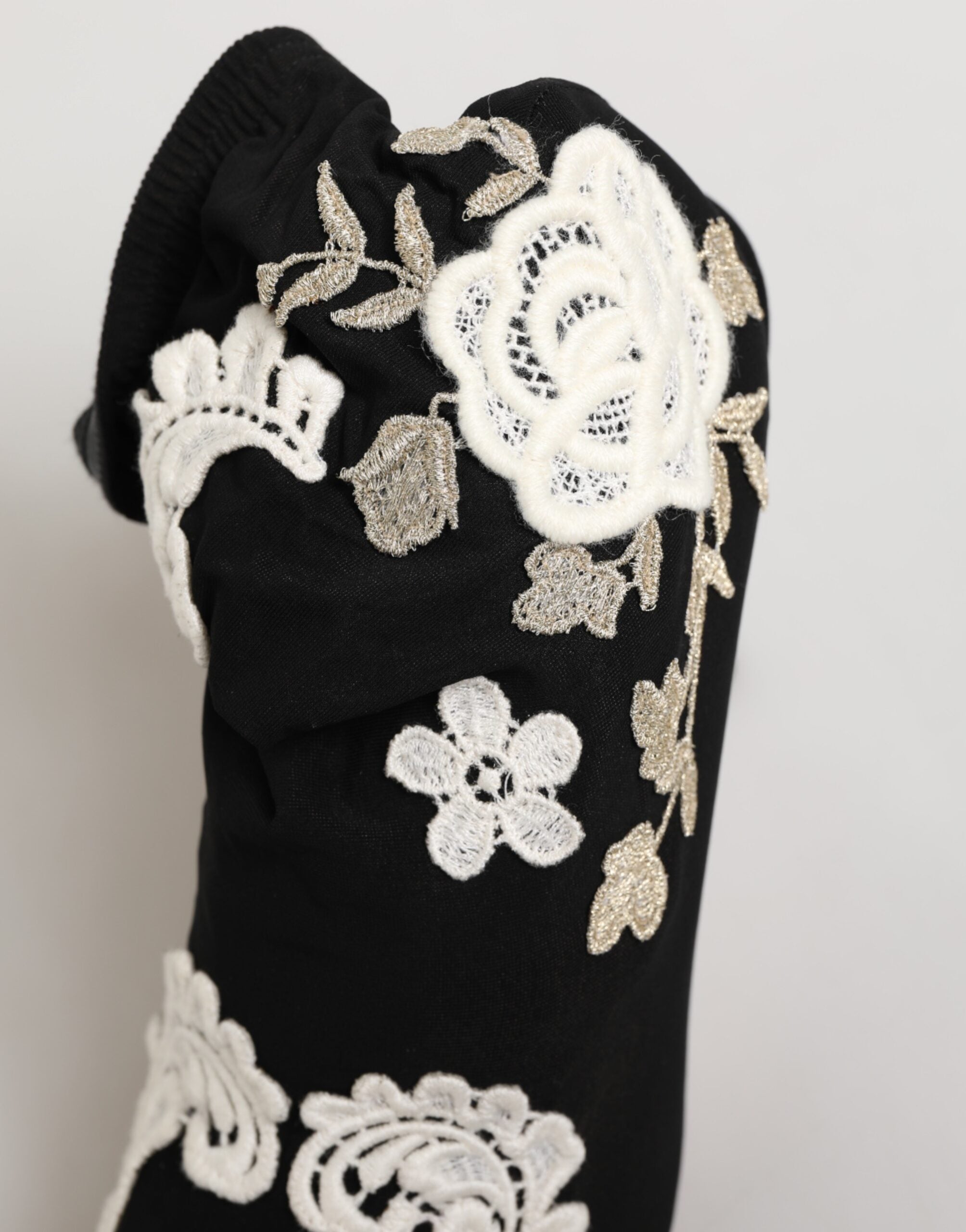 Black fabric boot with white floral lace and metallic embroidery detailing.