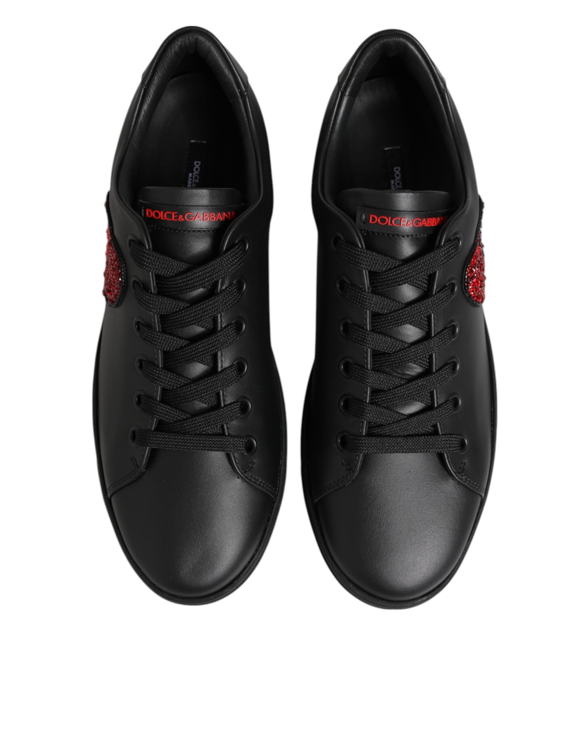 Black leather low-top sneakers with lace-up front, red crystal heart accents, and red Dolce & Gabbana tongue branding.