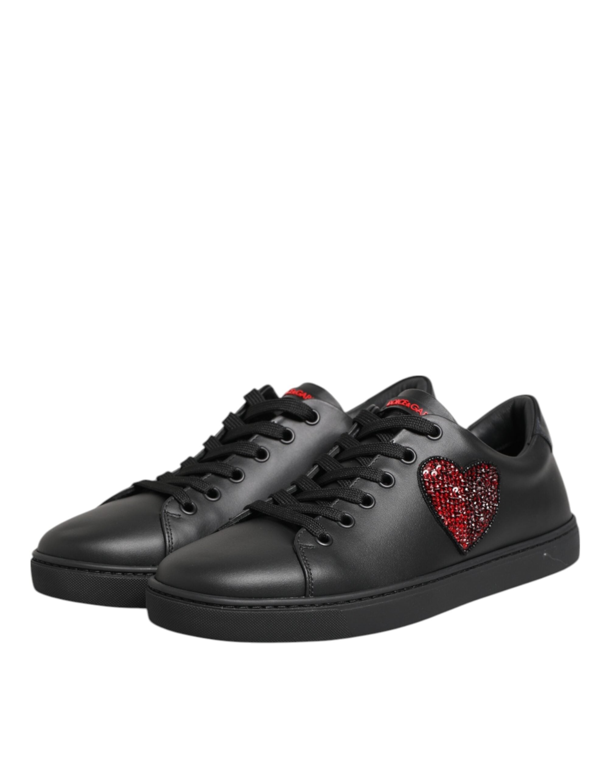 Black leather low-top sneakers with black laces and a red crystal-embellished heart detail on the side.