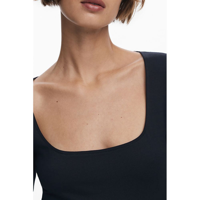 A woman wearing a black cotton dress with a square neckline