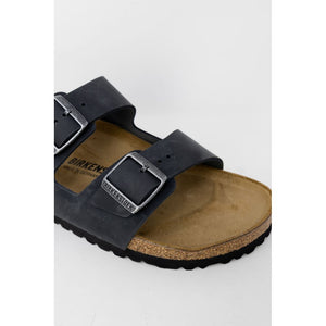 Black leather Birkenstock Arizona sandal with two adjustable metal buckles and a contoured cork footbed.