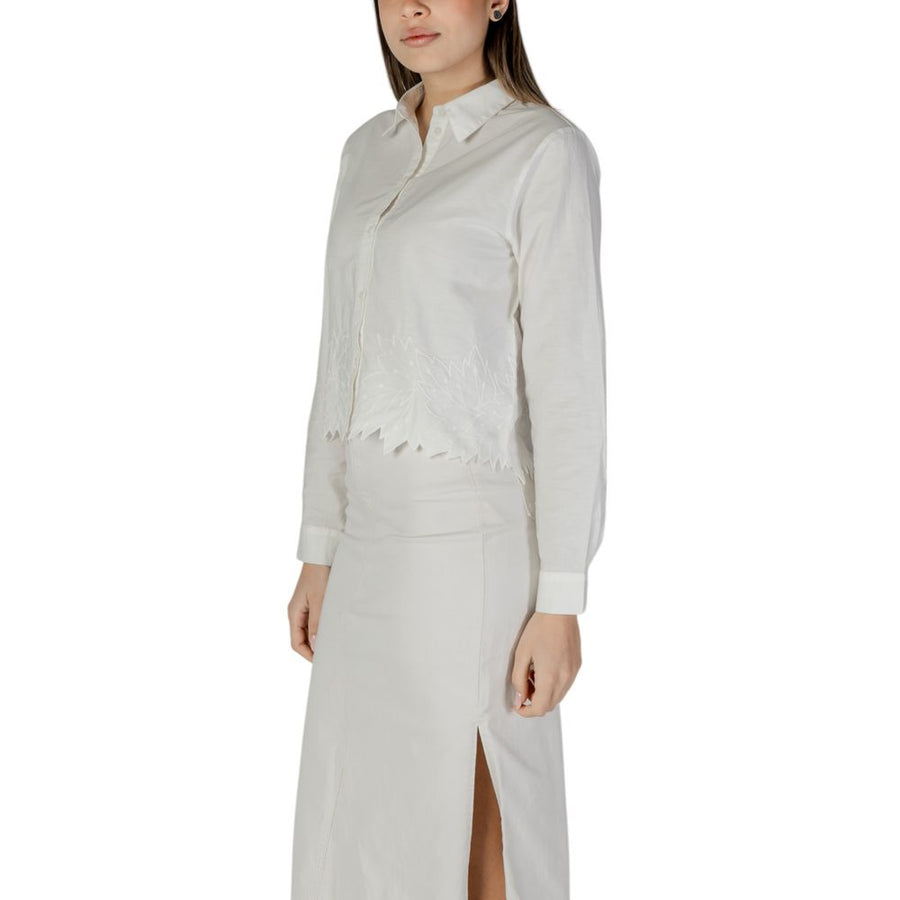 White cotton long-sleeve button-down blouse with a collared neck and embroidered leaf hem