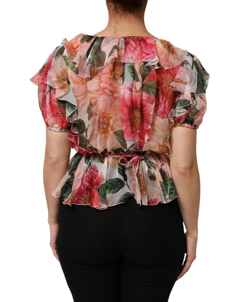 Pink floral silk blouse with short ruffled sleeves and a tie back worn over black pants